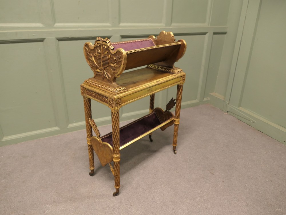 A gilded wooden two-tier book trough featuring spiral legs, carved cresting, and purple velvet lining. View V