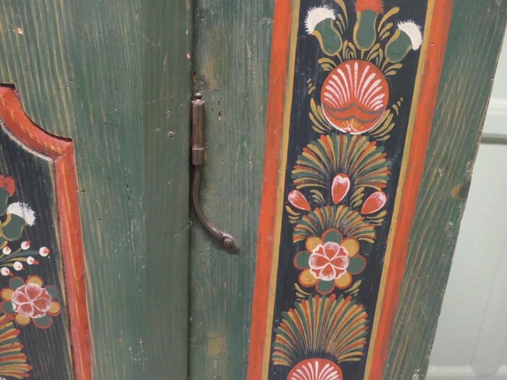 A dark green painted pine folk art dresser featuring an upper open plate rack and hand-painted floral panels on the drawers and lower door. View V