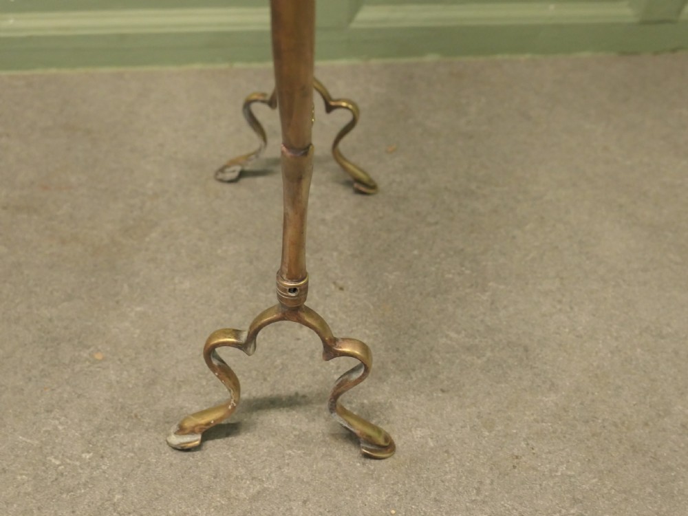 An Art Nouveau brass fire screen featuring a circular mirror frame topped with an intricate whiplash crest and resting on two curved metal legs. View VII