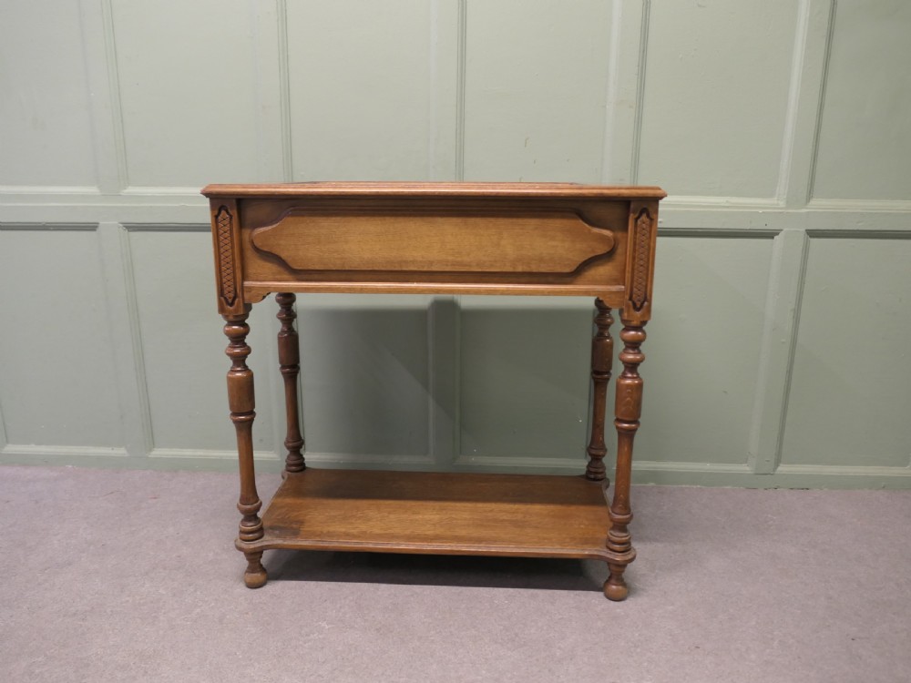 A French Arts and Crafts golden oak jardiniere stand featuring a recessed metal trough liner, carved corner detailing, turned legs, and a lower shelf. View III