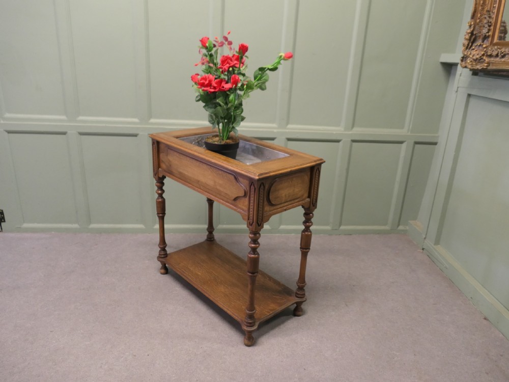 A French Arts and Crafts golden oak jardiniere stand featuring a recessed metal trough liner, carved corner detailing, turned legs, and a lower shelf. View V
