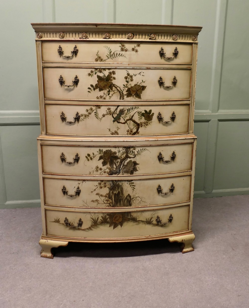 A cream-painted tallboy chest on chest featuring hand-painted Chinoiserie botanical motifs across six drawers with brass bail handles.