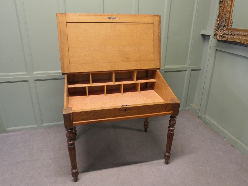 An antique French oak clerks desk featuring a slanted hinged writing surface, a upper gallery shelf, and four turned legs. View IV