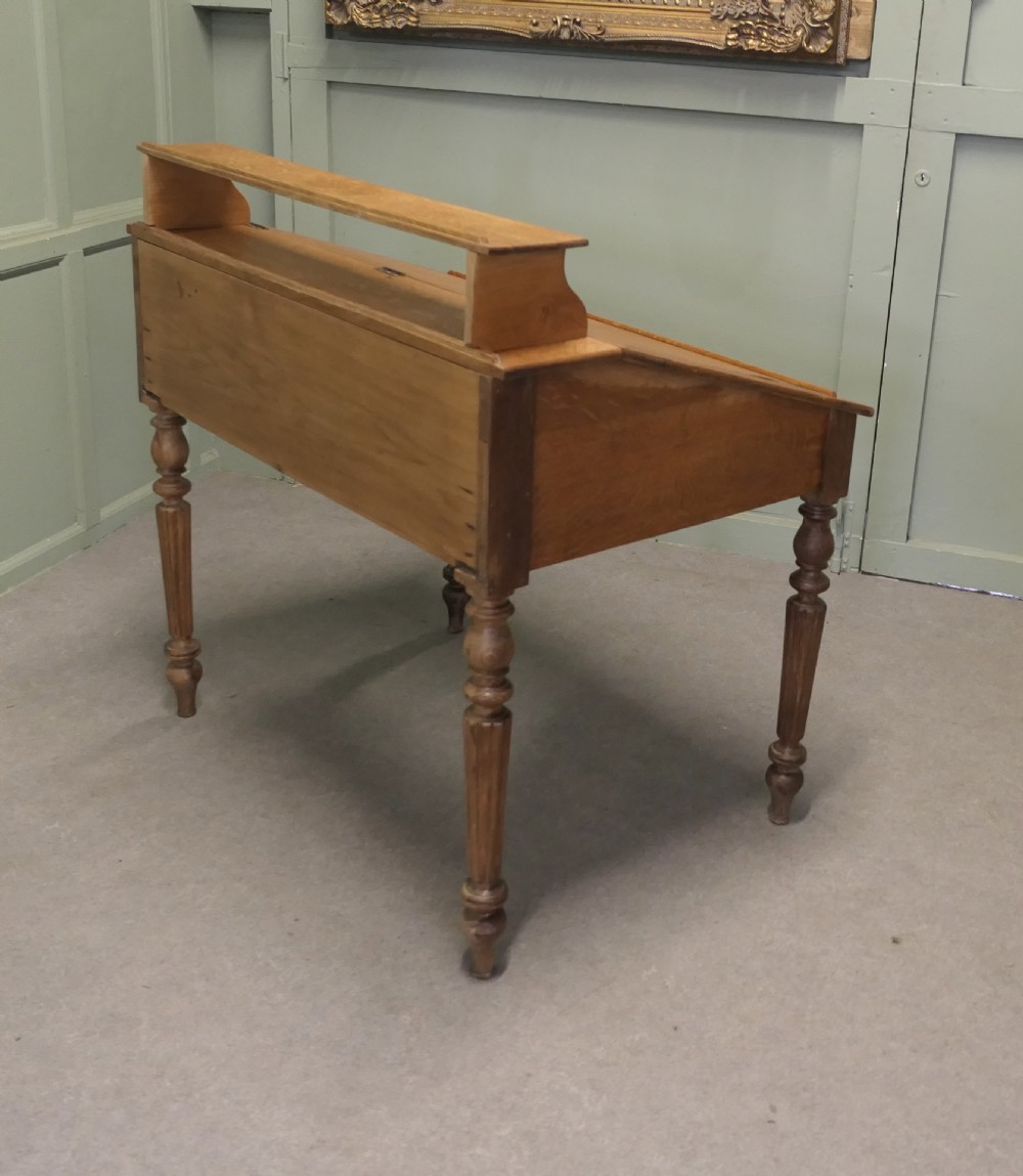 An antique French oak clerks desk featuring a slanted hinged writing surface, a upper gallery shelf, and four turned legs. View V