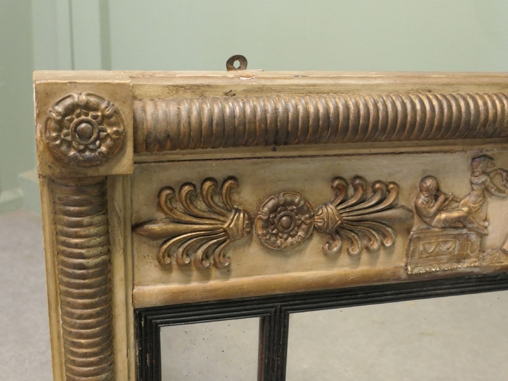 A horizontal Regency style triple plate overmantel mirror with a classical relief frieze, reeded side columns, and corner rosettes. View II