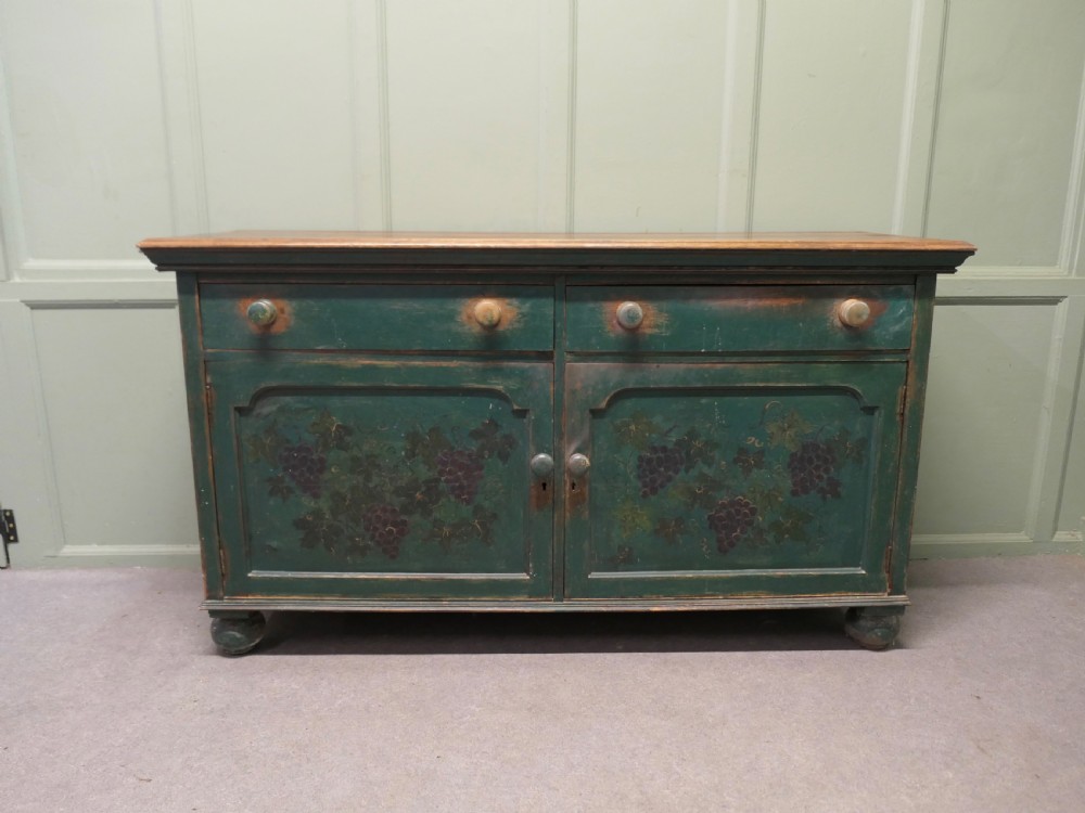 A Victorian green painted wooden dresser base with two drawers, two lower cabinet doors featuring hand-painted grape motifs, and a natural wood top surface. View III