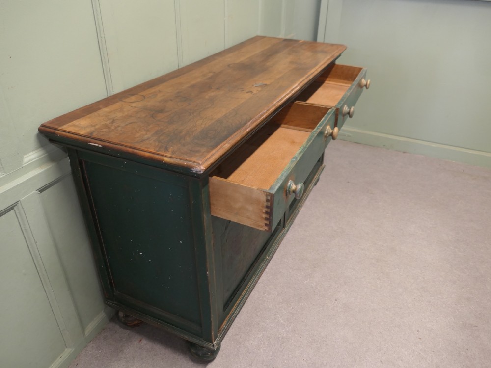 A Victorian green painted wooden dresser base with two drawers, two lower cabinet doors featuring hand-painted grape motifs, and a natural wood top surface. View IV