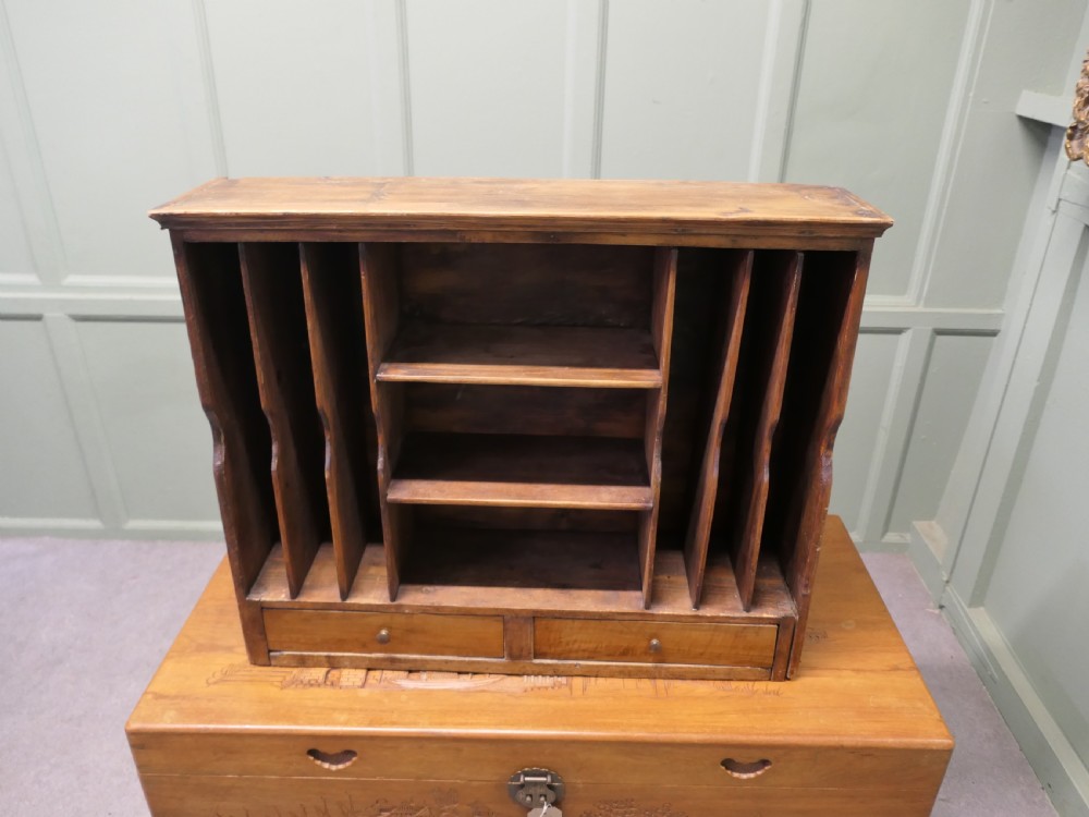 A warm brown wooden desk organiser with vertical document slots, central shelves, and two small drawers at the base.