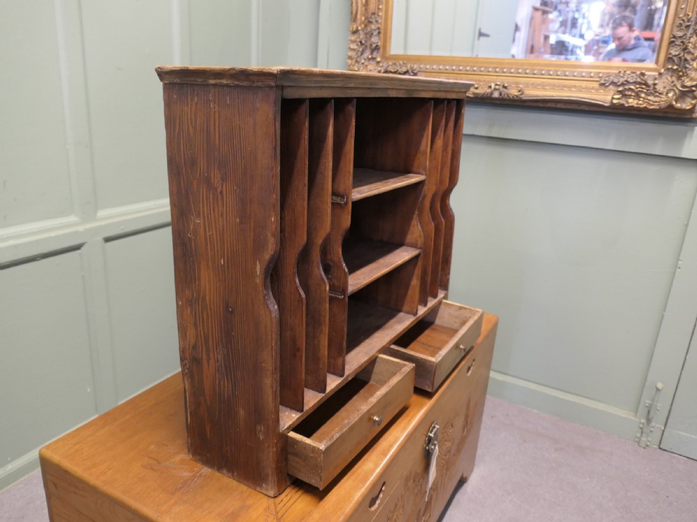 A warm brown wooden desk organiser with vertical document slots, central shelves, and two small drawers at the base. View II