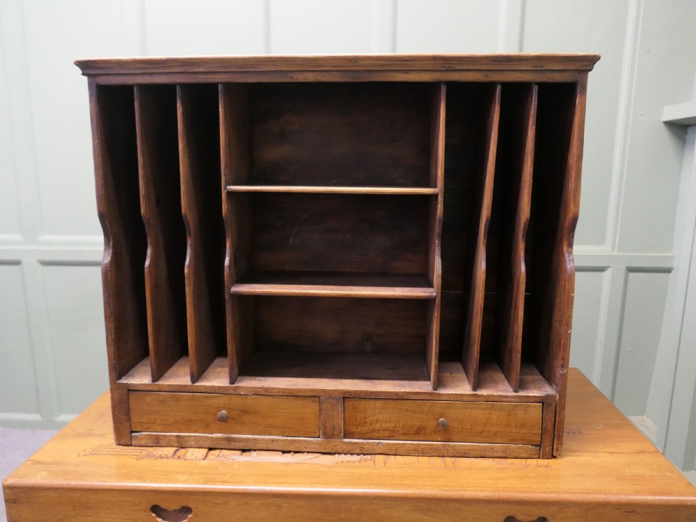 A warm brown wooden desk organiser with vertical document slots, central shelves, and two small drawers at the base. View V