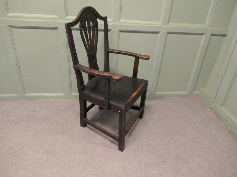A dark hand-carved Chippendale style armchair featuring a pierced back splat, carved armrests, geometric leg carving, and a relief-carved lower seat apron. View V