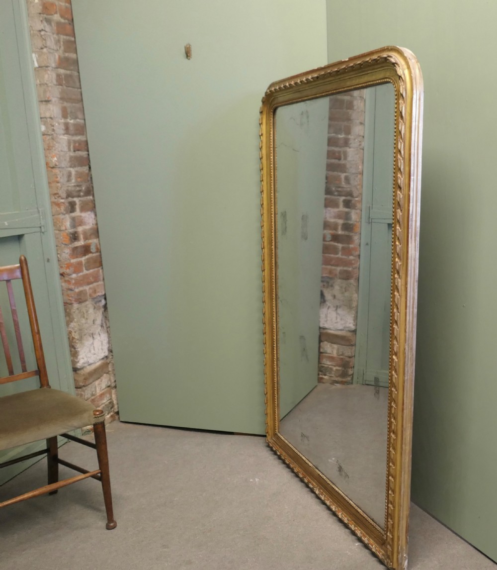 A large 19th-century French Louis Philippe wall mirror featuring a gilded frame with rounded upper corners, beaded inner border, and foxed mirror glass. View III