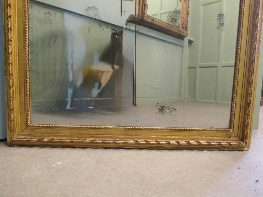 A large 19th-century French Louis Philippe wall mirror featuring a gilded frame with rounded upper corners, beaded inner border, and foxed mirror glass. View V
