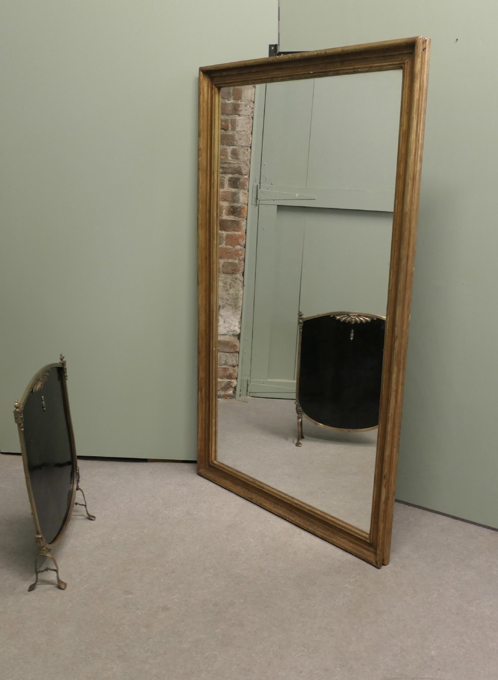 A tall rectangular French mirror framed in a simple moulded border with an aged gold leaf finish.