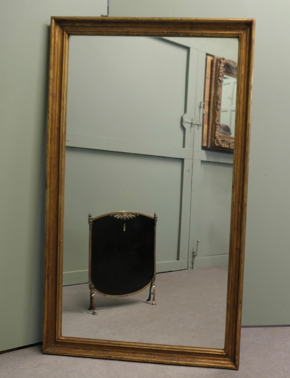 A tall rectangular French mirror framed in a simple moulded border with an aged gold leaf finish. View II