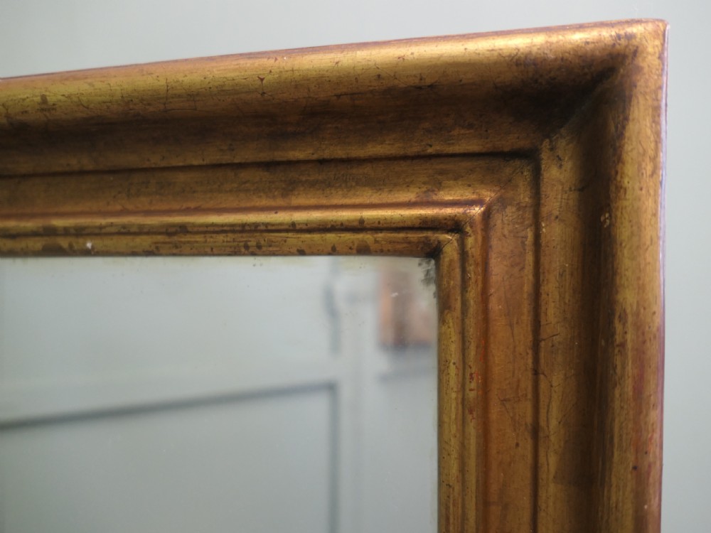 A tall rectangular French mirror framed in a simple moulded border with an aged gold leaf finish. View IV