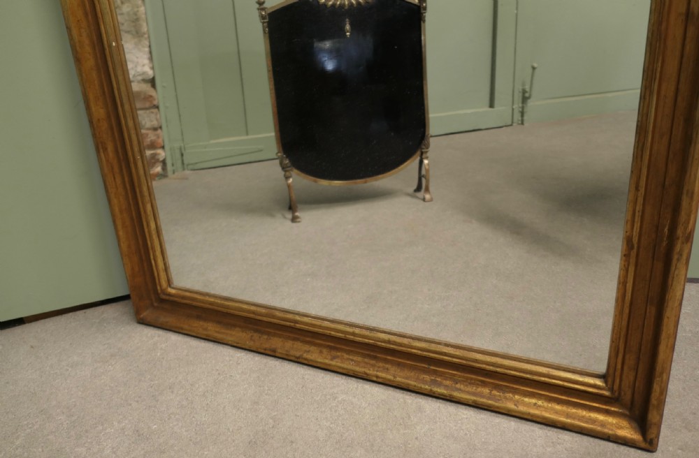 A tall rectangular French mirror framed in a simple moulded border with an aged gold leaf finish. View V