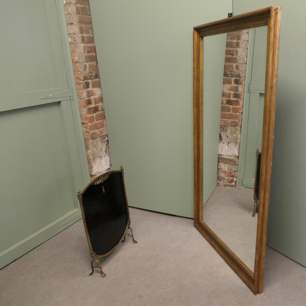 A tall rectangular French mirror framed in a simple moulded border with an aged gold leaf finish. View VI