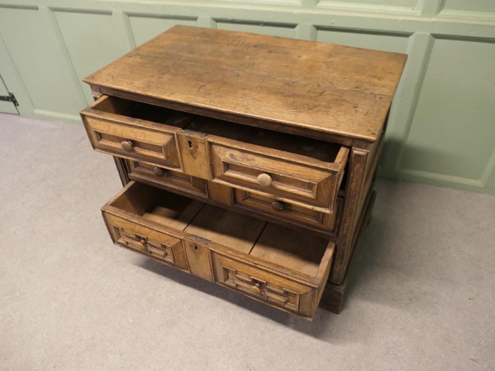 A seventeenth-century oak chest featuring three drawers with geometric moulded fronts, wooden turned knobs, and panelled sides. View II