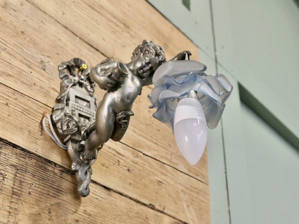 A pair of cast metal wall sconces shaped as figurative cherubs supporting soft blue flower-formed glass shades. View IV