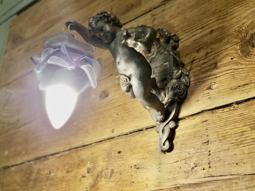 A pair of cast metal wall sconces shaped as figurative cherubs supporting soft blue flower-formed glass shades. View VI