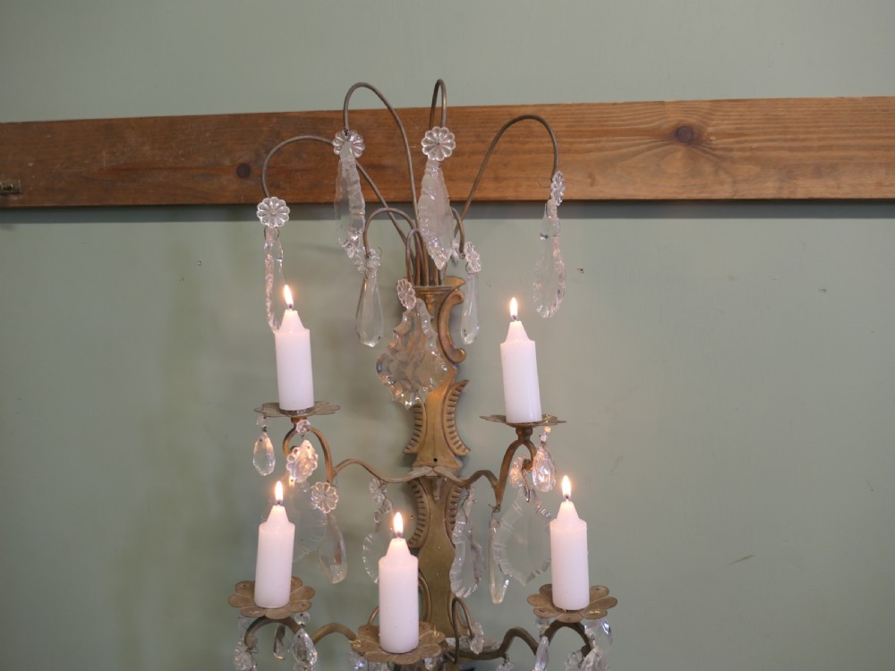 A 19th-century French brass wall sconce candelabra featuring four candle holders and clear crystal glass droplets. View VI