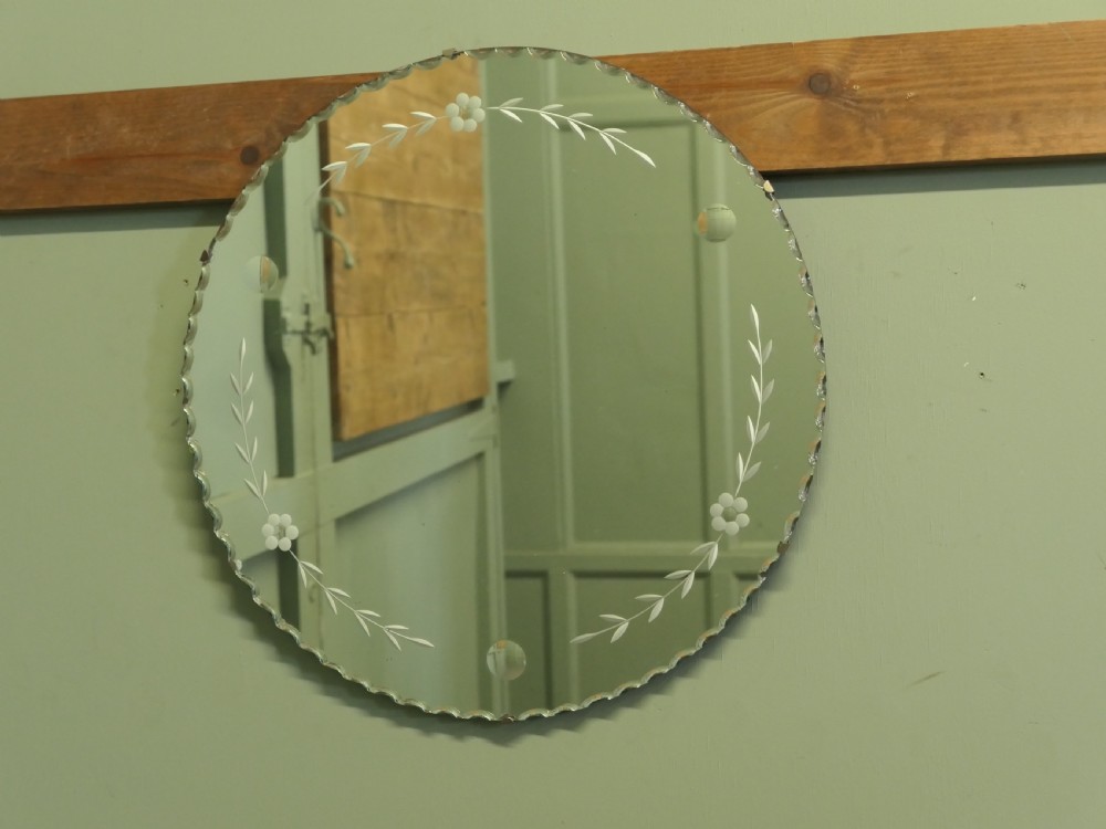 A circular frameless glass wall mirror featuring etched floral garlands along the inner border and a scalloped outer rim. View III