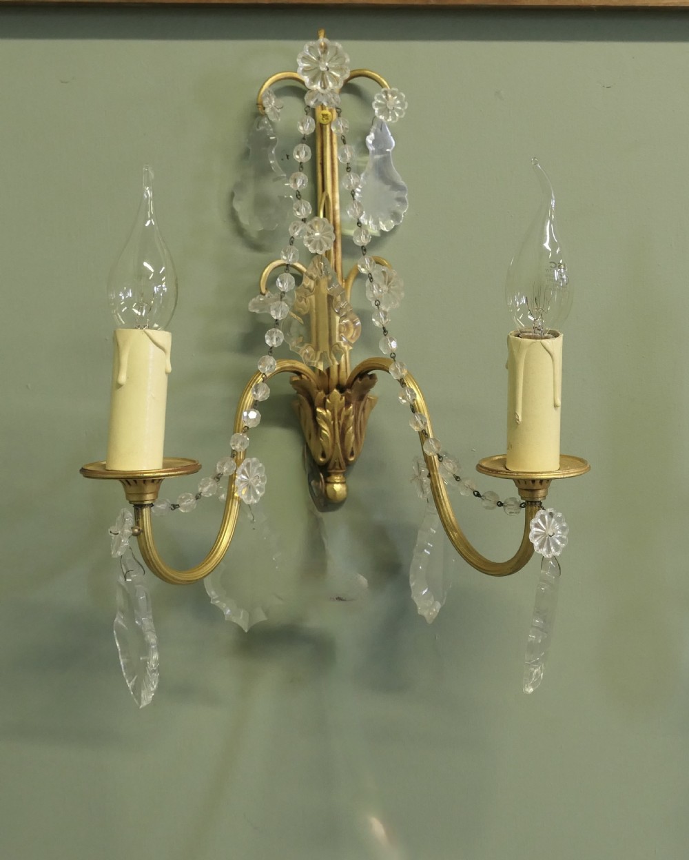 A pair of twin-arm gilt brass French wall sconces decorated with crystal garlands, faceted drops, and candle-effect fittings. View VI