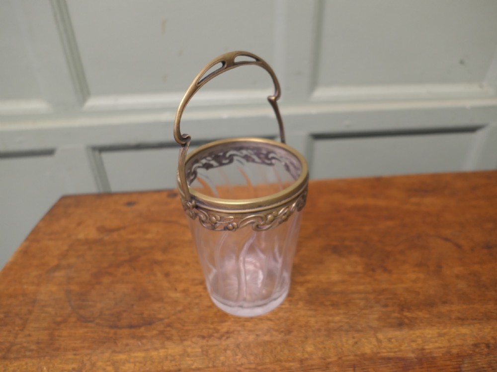 A small French Art Nouveau clear glass personal ice bucket featuring spiral fluted sides and an ornate brass collar with a swing handle. View VI