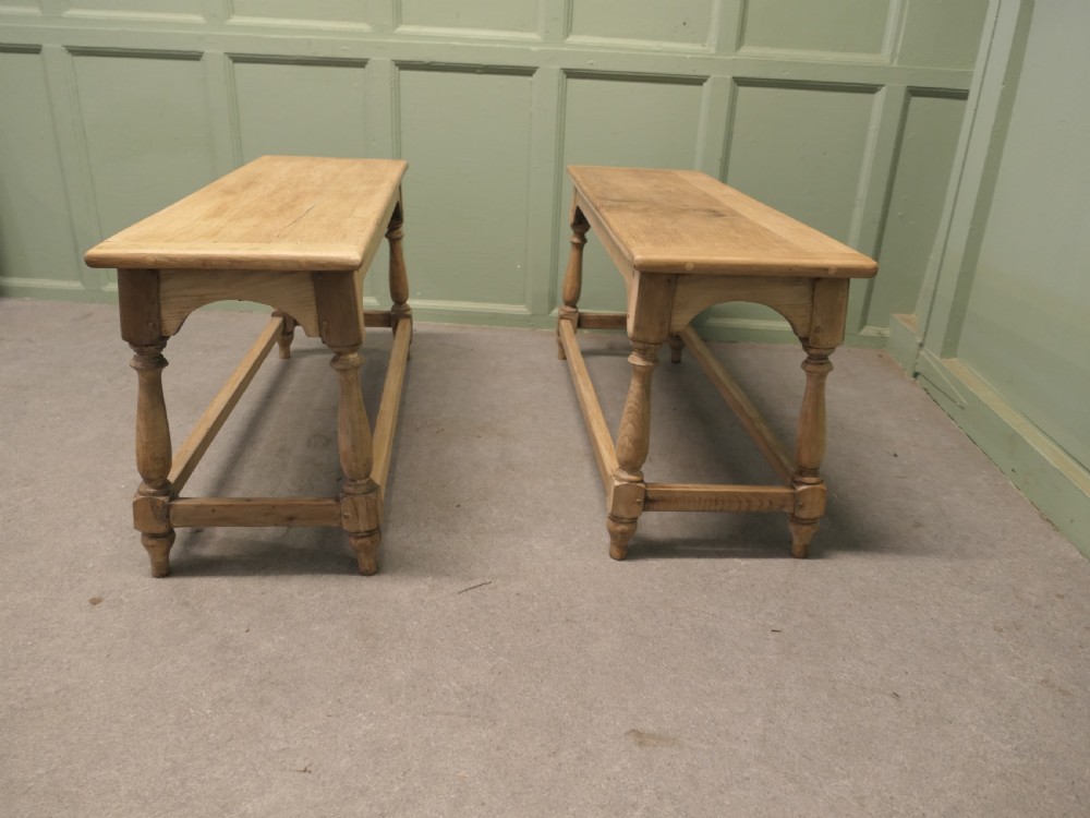 A pair of matching long bleached oak joint benches featuring turned legs, box stretchers, and arched aprons.