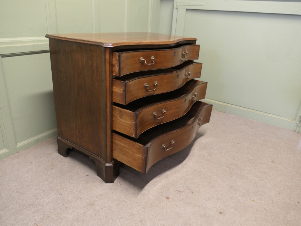 A Georgian serpentine-fronted walnut chest of drawers featuring four graduated drawers with brass swan-neck handles. View II