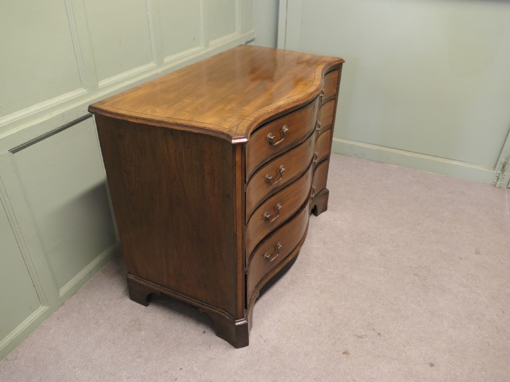 A Georgian serpentine-fronted walnut chest of drawers featuring four graduated drawers with brass swan-neck handles. View IV