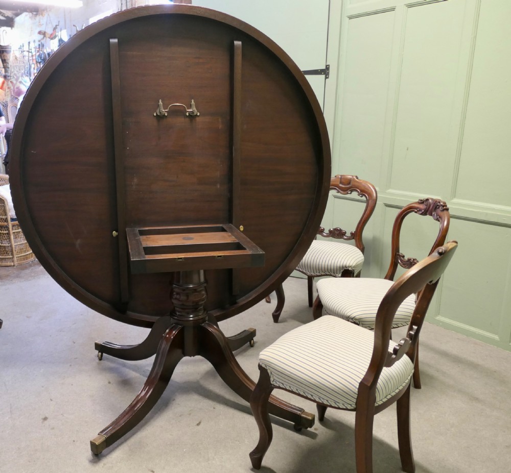 A circular dark mahogany dining table surrounded by eight matching carved balloon-back dining chairs with blue and white striped fabric seats. View IV