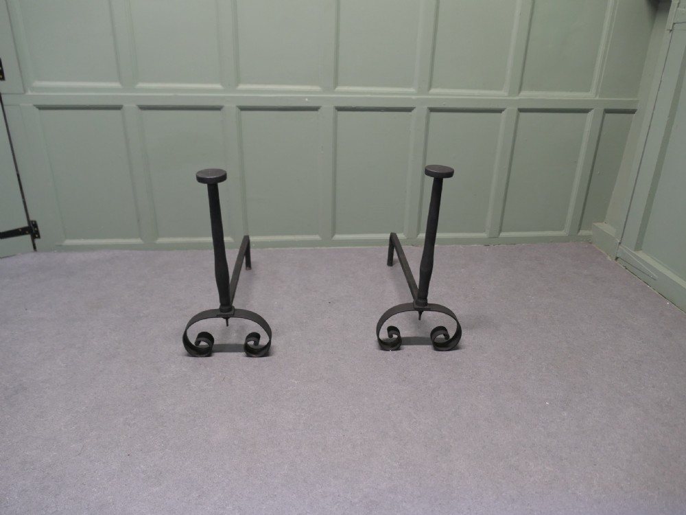 A pair of tall dark iron andirons featuring scrolled pedestal bases and vertical upright pillars with flat caps. View II