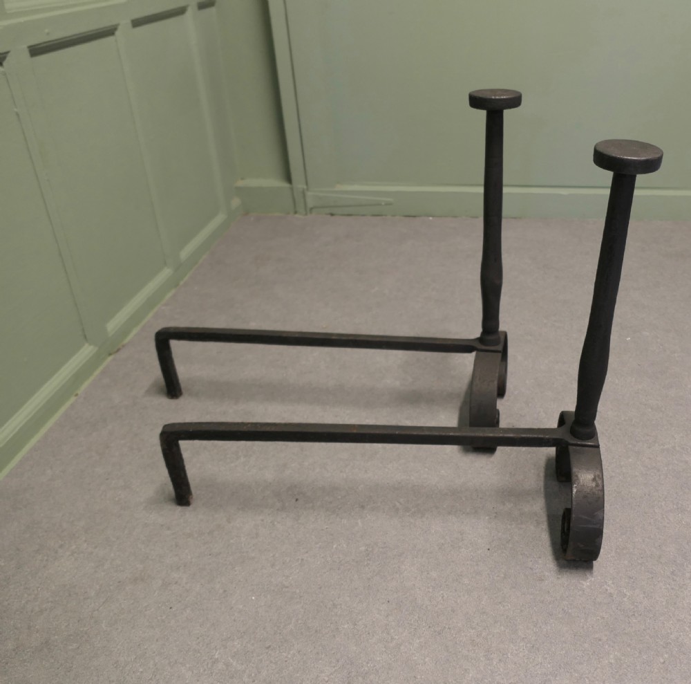 A pair of tall dark iron andirons featuring scrolled pedestal bases and vertical upright pillars with flat caps. View VI