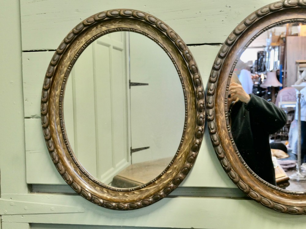 A pair of matching oval wall mirrors featuring carved egg-and-dart borders with a brown simulated wood grain paint finish. View III