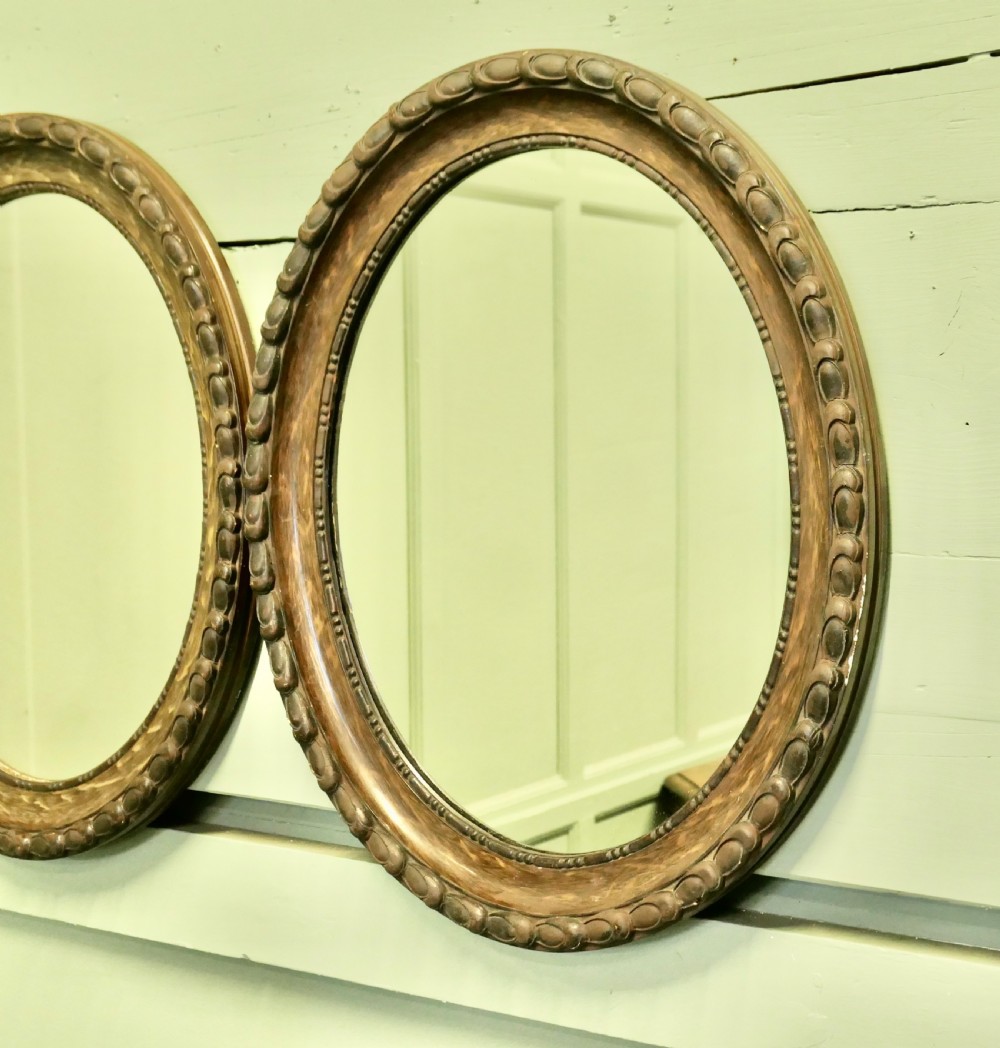 A pair of matching oval wall mirrors featuring carved egg-and-dart borders with a brown simulated wood grain paint finish. View IV