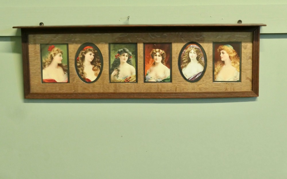 A horizontal dark oak wall shelf featuring six mounted Pre-Raphaelite style female portraits set behind alternating rectangular and oval apertures.