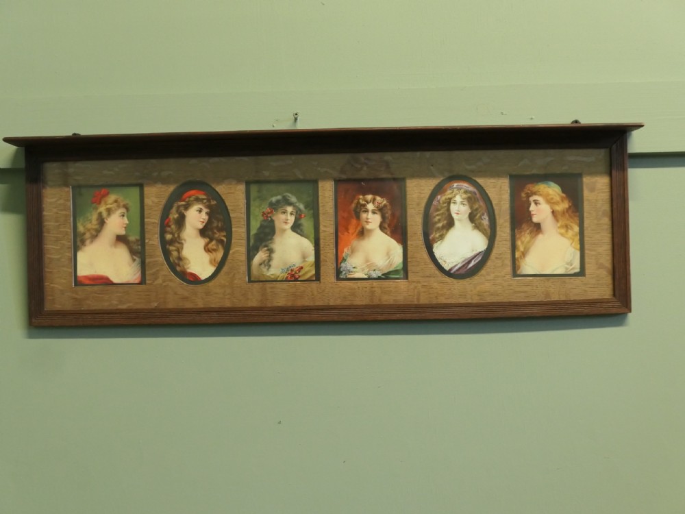 A horizontal dark oak wall shelf featuring six mounted Pre-Raphaelite style female portraits set behind alternating rectangular and oval apertures. View II