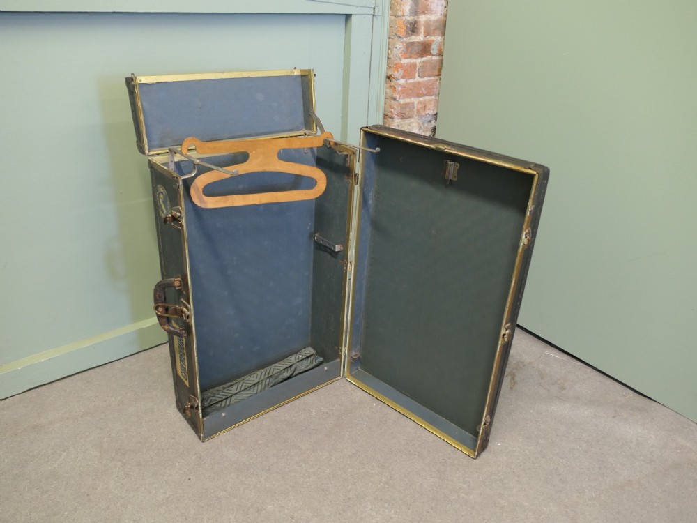 A black canvas cabin trunk featuring brass latches, riveted edges, a central handle, and original Cunard Line Cherbourg travel labels. View III