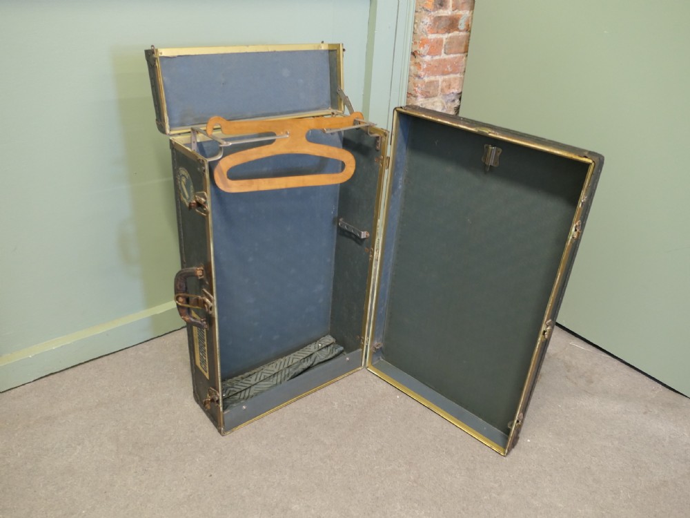 A black canvas cabin trunk featuring brass latches, riveted edges, a central handle, and original Cunard Line Cherbourg travel labels. View IV