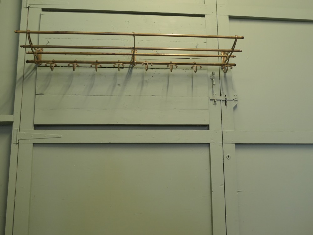 A 5ft French Art Deco brass wall-mounted hat and coat rack featuring an upper slatted shelf rail and eight sliding double hooks. View IV