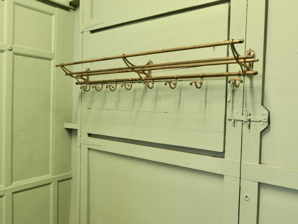 A 5ft French Art Deco brass wall-mounted hat and coat rack featuring an upper slatted shelf rail and eight sliding double hooks. View V
