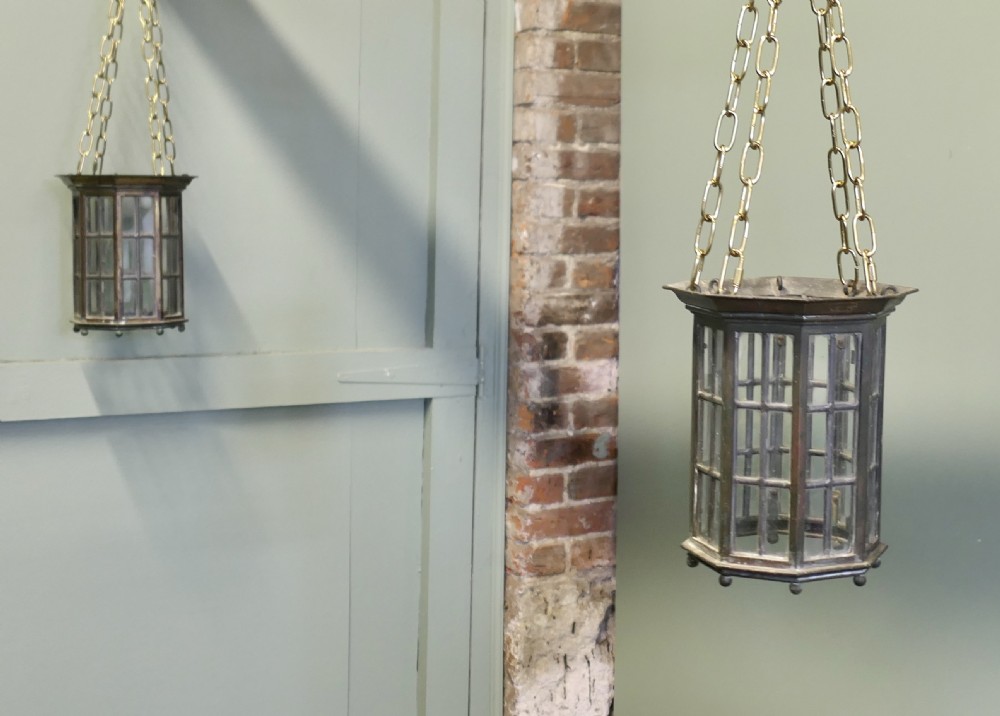 A pair of 19th-century dark bronze hexagonal lanterns with glass panes suspended by brass chains.