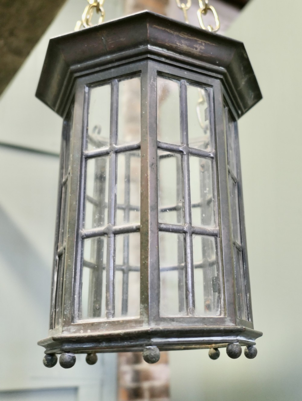 A pair of 19th-century dark bronze hexagonal lanterns with glass panes suspended by brass chains. View IV