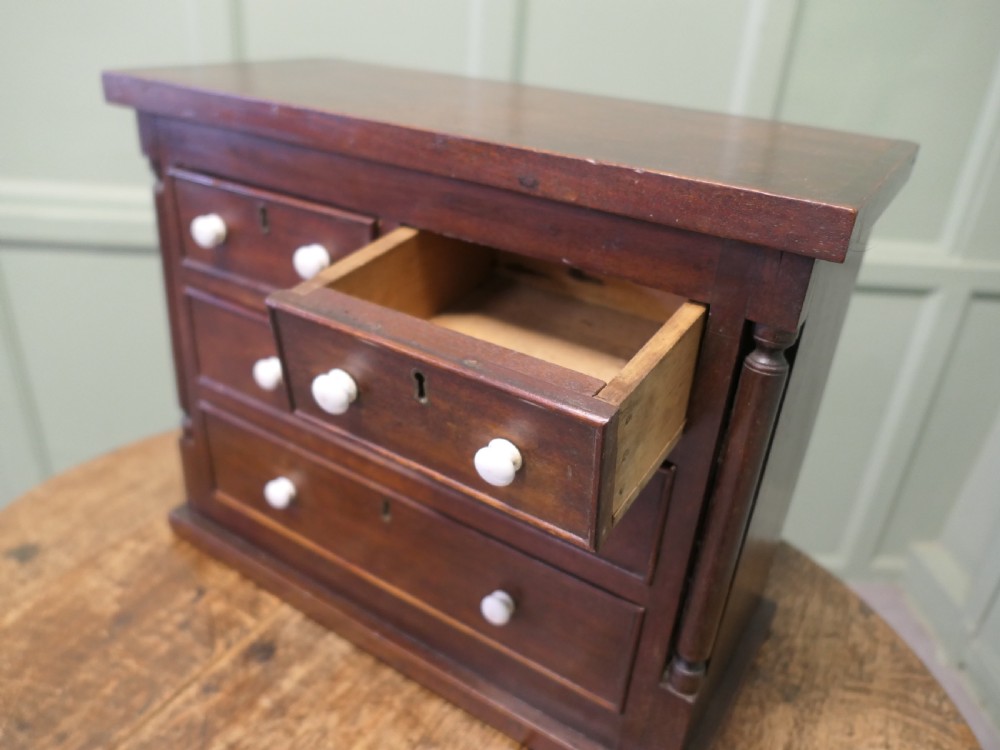 A 19th-century mahogany miniature Scotch chest featuring white knobs, side columns, and multiple drawer tiers. View II
