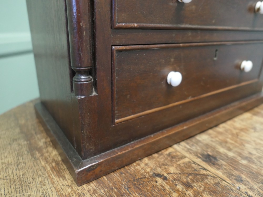 A 19th-century mahogany miniature Scotch chest featuring white knobs, side columns, and multiple drawer tiers. View III