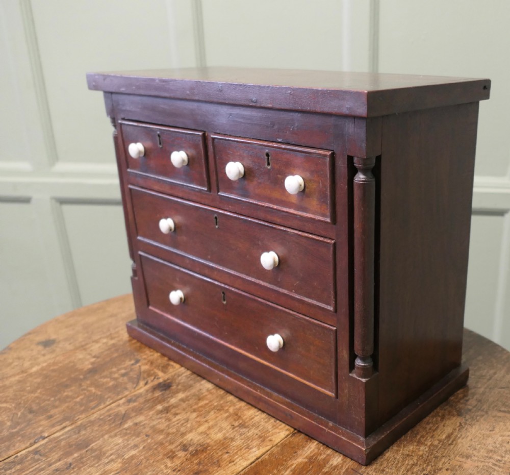 A 19th-century mahogany miniature Scotch chest featuring white knobs, side columns, and multiple drawer tiers. View IV