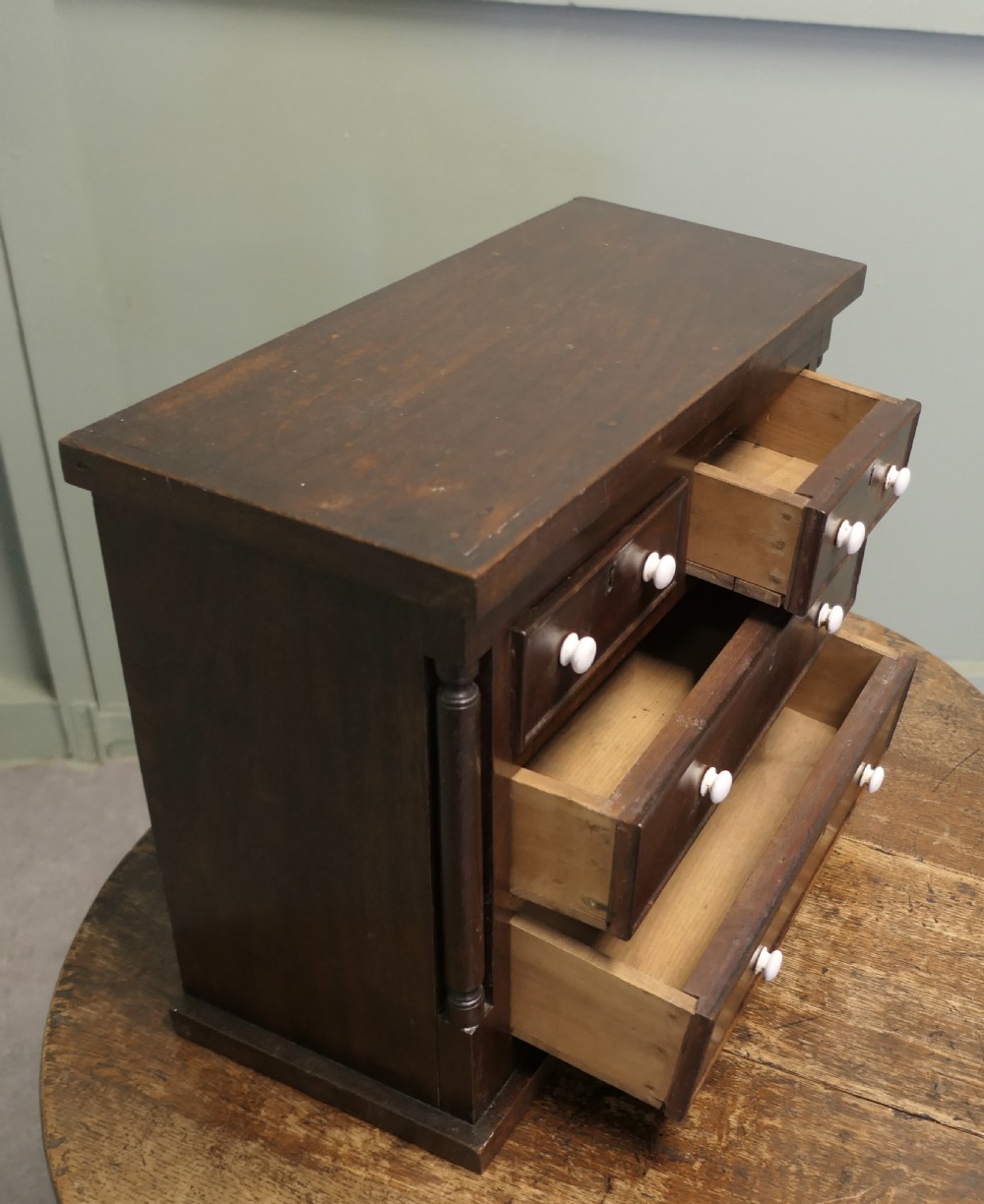 A 19th-century mahogany miniature Scotch chest featuring white knobs, side columns, and multiple drawer tiers. View VI