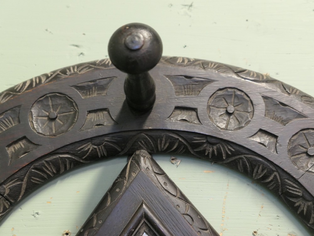 A dark carved oak horseshoe-shaped wall rack featuring five turned wooden coat pegs and a central diamond-shaped mirror. View II